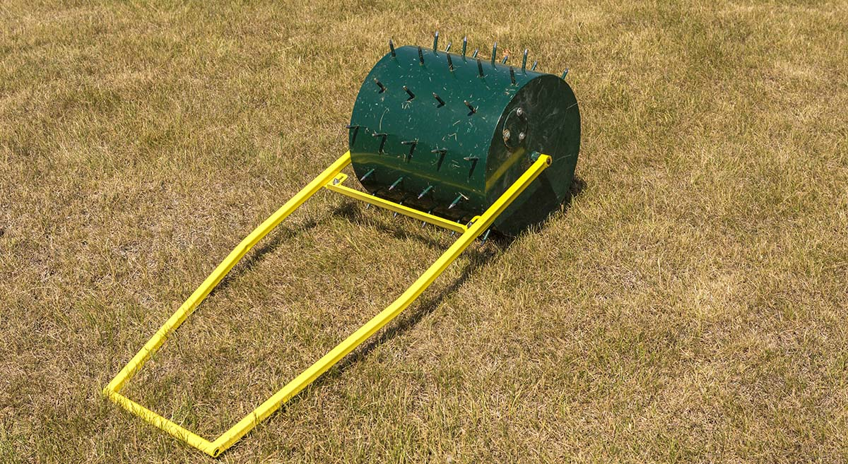 aerator wałek z kolcami na zielonej trawie do aeracji trawnika