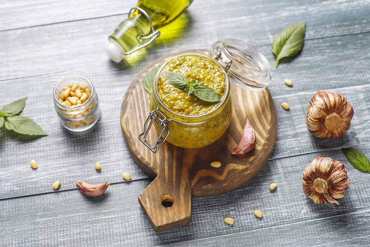 Pesto z pędów czosnku - przepis czerwcowy Domowe pesto z pędów czosnku w słoiczku na drewnianej desce